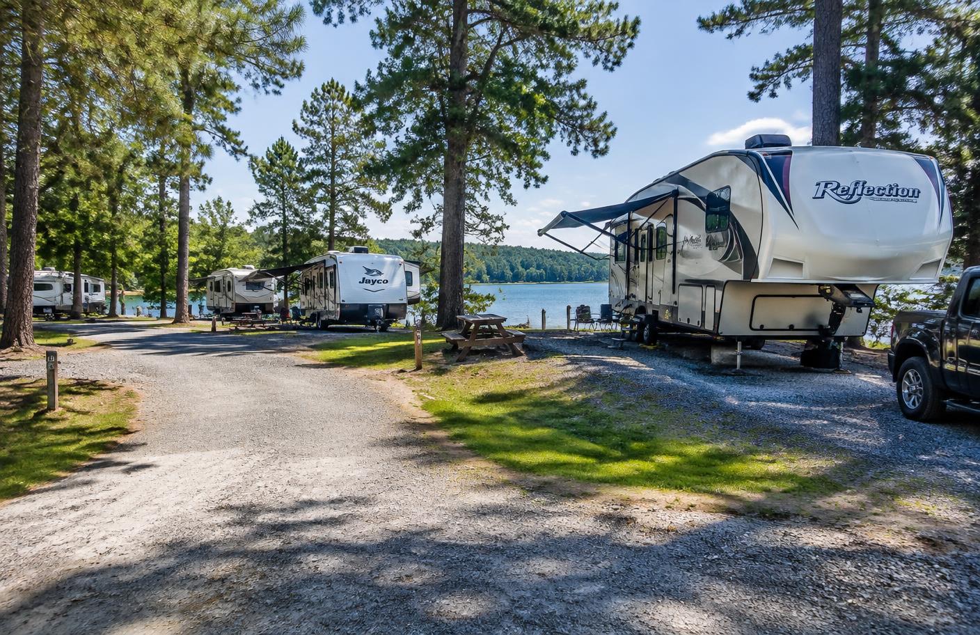 Travel trailers and fifth wheels parked at a lakeside campground loop near Lake Lanier